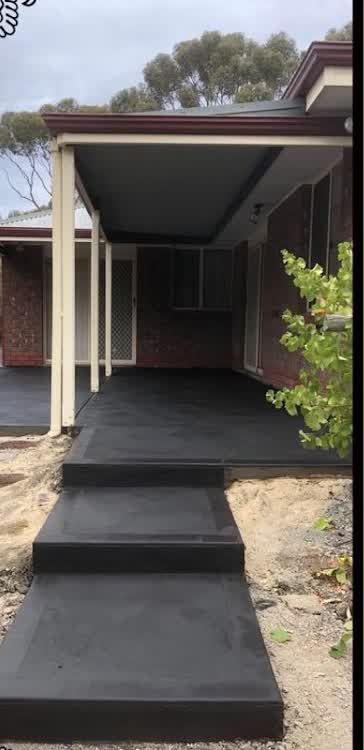 A charcoal-stained patio and steps poured up to the front door of a brick home