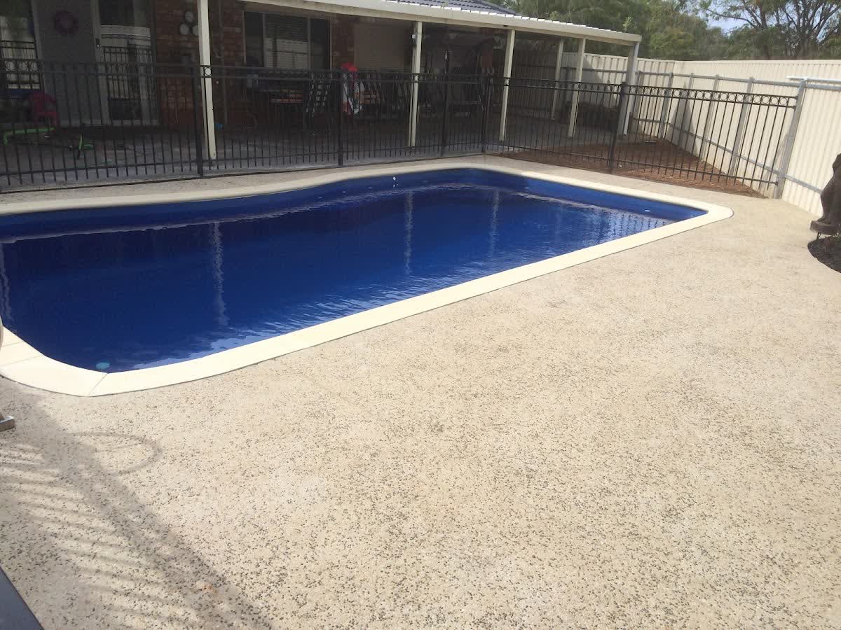 A second pool surround finished in pale exposed aggregate, framed by a timber deck